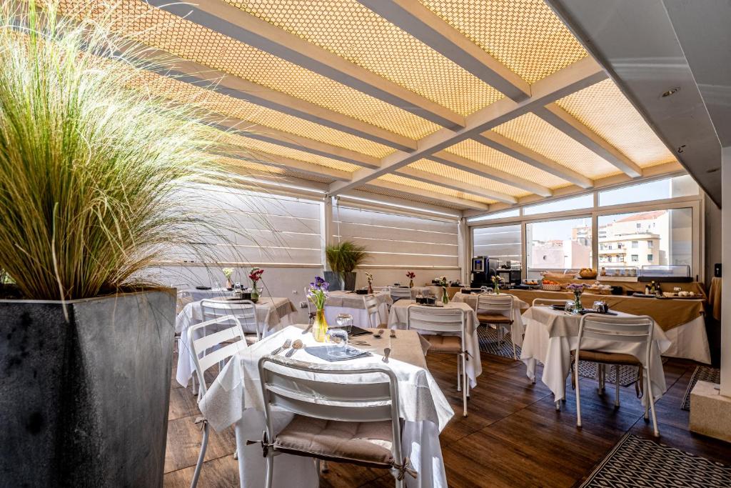 a restaurant with white tables and chairs and windows at Neko Boutique Hotel in Cagliari