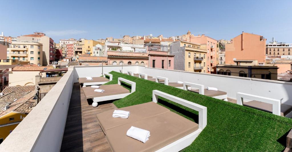 a balcony with tables and grass on a city at Neko Boutique Hotel in Cagliari