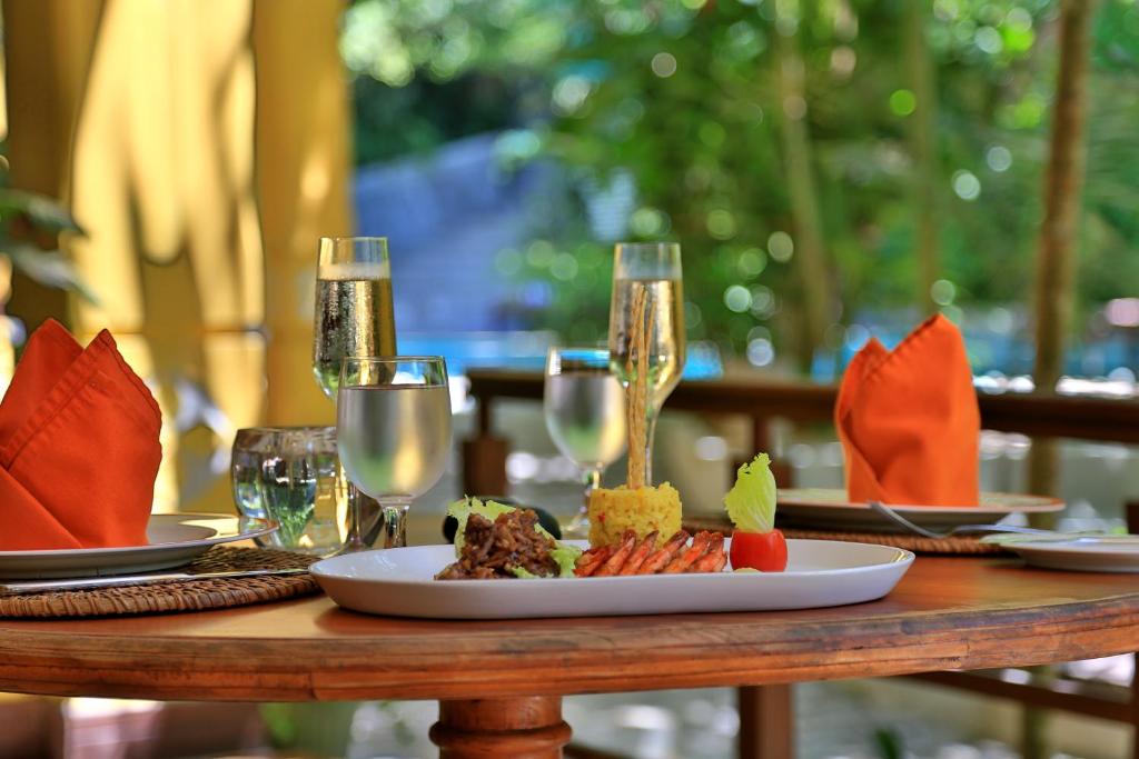 a table with a plate of food and wine glasses at Thambapanni Retreat in Unawatuna