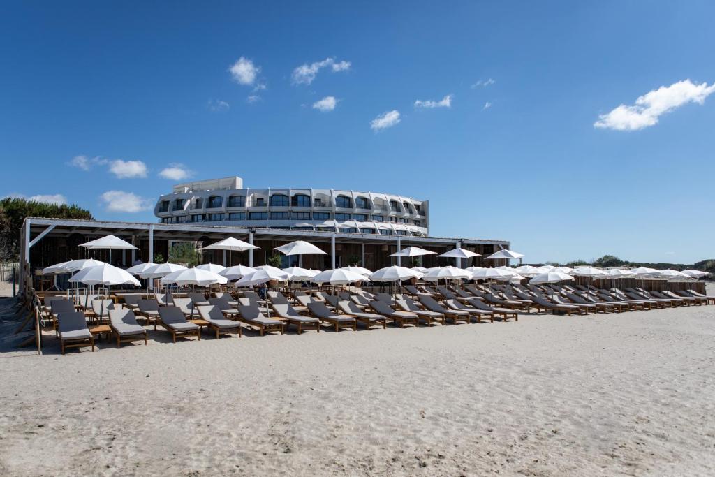 eine Gruppe von Stühlen und Sonnenschirmen am Strand in der Unterkunft Hôtel La Plage 5 étoiles La Grande Motte in La Grande-Motte