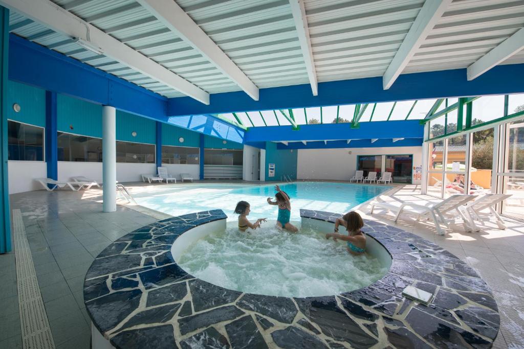 three children playing in a hot tub in a swimming pool at Les Villas des Pins in Saint-Hilaire-de-Riez