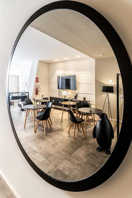 a mirror reflecting a room with tables and chairs at Neko Boutique Hotel in Cagliari
