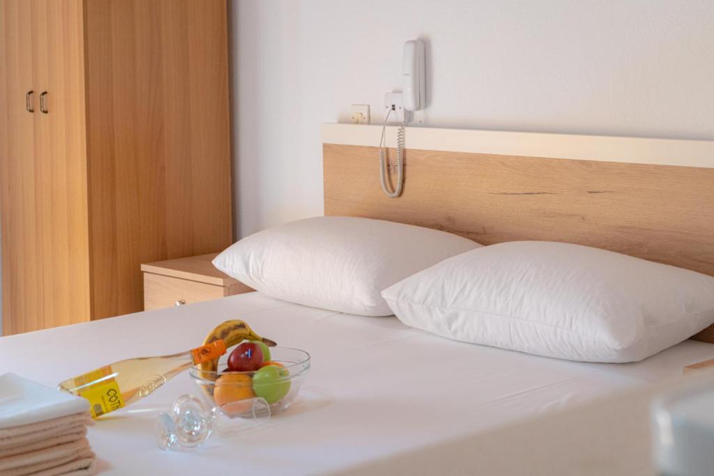 a bed with two pillows and a bowl of fruit on it at HOTEL PAVLOS in Paralia Katerinis