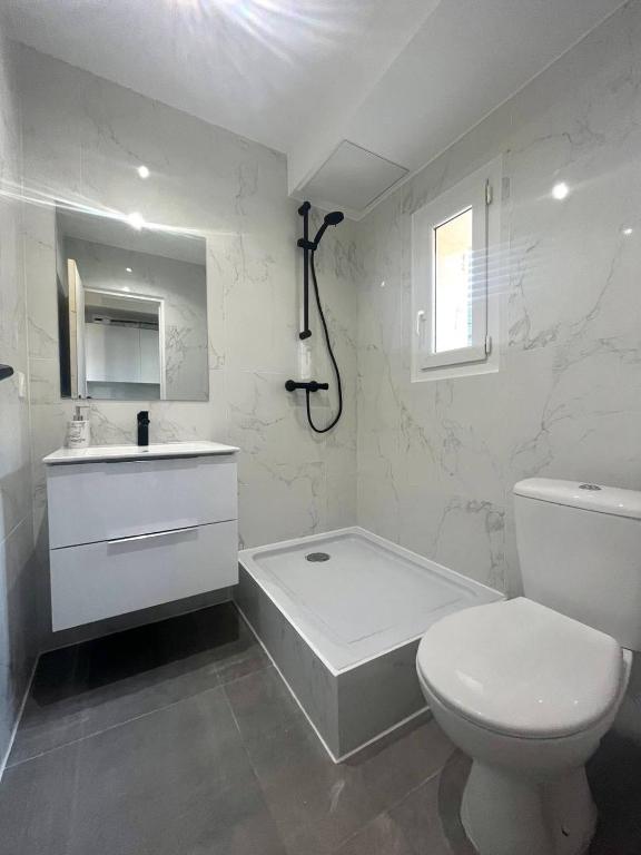 a white bathroom with a toilet and a bath tub at Designed flat in Menton center in Menton