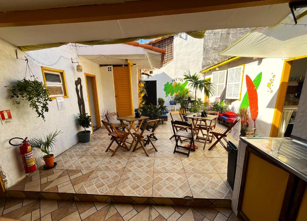 un patio al aire libre con sillas, mesas y una sombrilla en Hostel casa da ana en Búzios