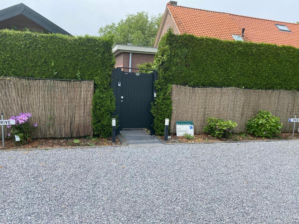 a driveway with a black gate and a fence at La-Perchade in Huissen