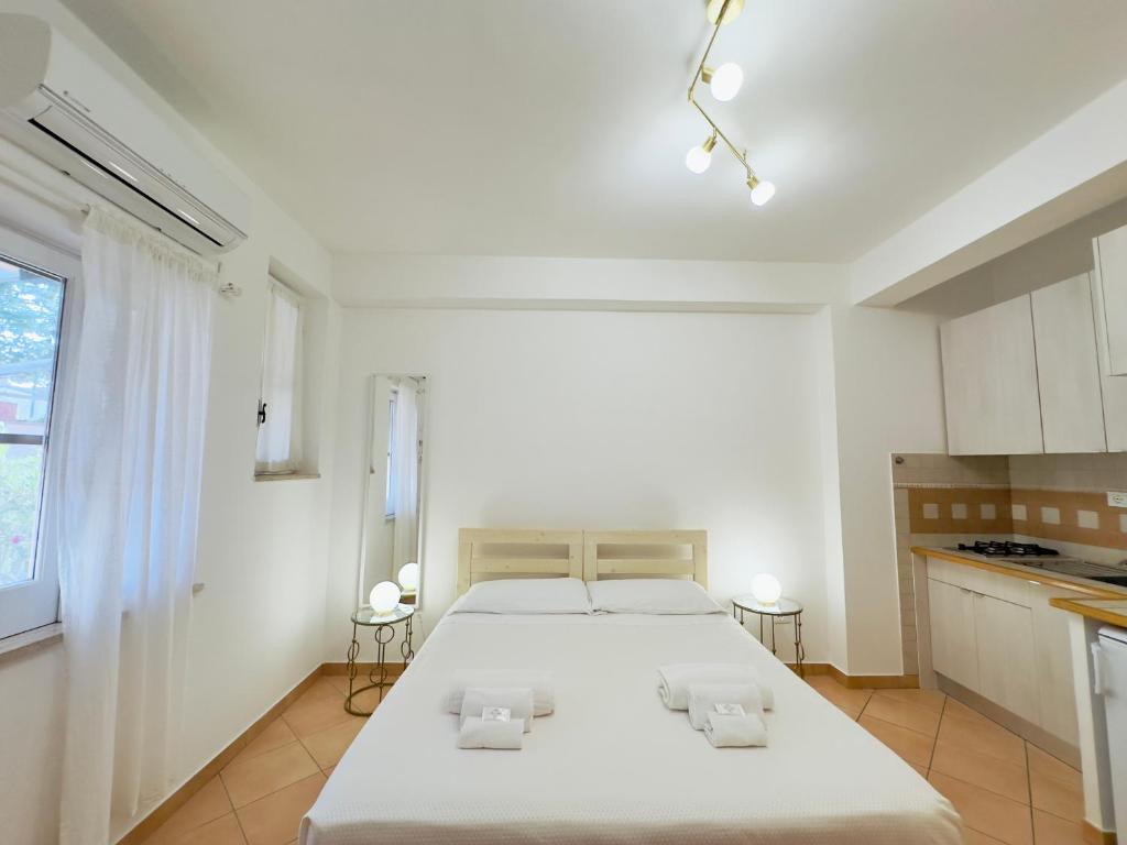 um quarto branco com uma cama e uma cozinha em ELLE Monolocale - Sperlonga 50 mt dalla spiaggia con parcheggio em Sperlonga
