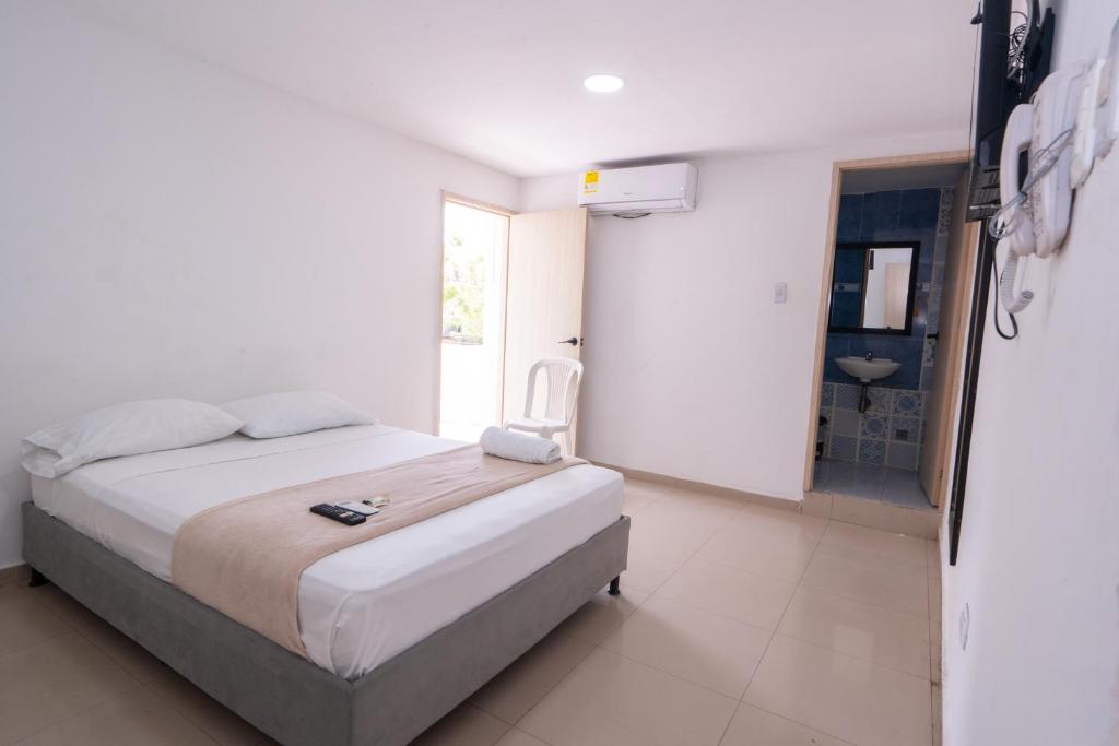Habitación blanca con cama y baño. en Hotel Imperial House, en Barranquilla