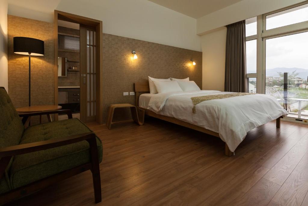um quarto com uma cama, uma cadeira e uma janela em I Leisure B&B em Yuanshan