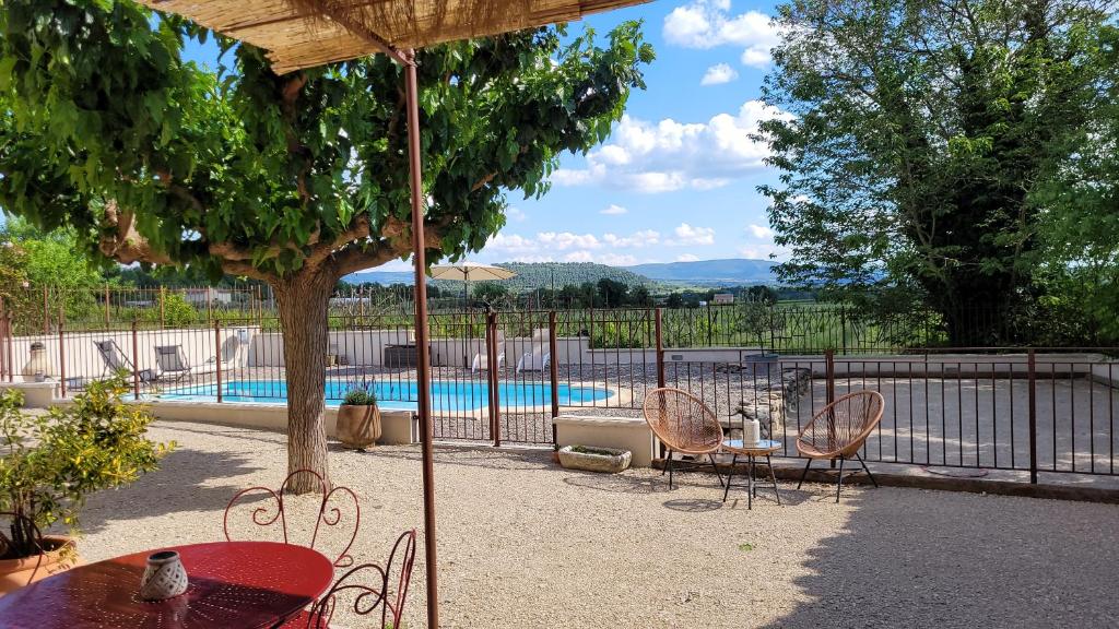 eine Terrasse mit einem Tisch und Stühlen neben einem Pool in der Unterkunft Gîte La Genestière au milieu des vignes, piscine partagée in Mazan