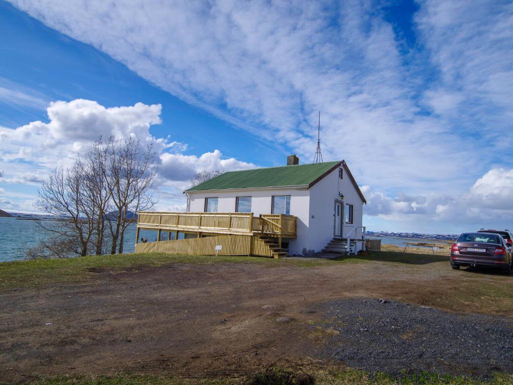 GeiteyjarstrondMyvo The House Geiteyjarströnd 4的一栋靠近水边的带有绿色屋顶的白色房屋