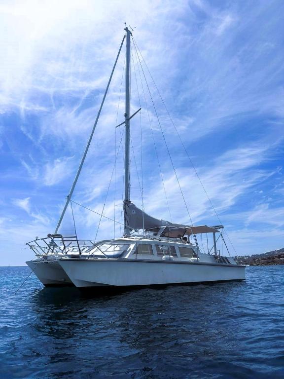 un bateau blanc assis dans l'eau sur l'océan dans l'établissement Nuit insolite - Bateau Logement Catamaran AVENTURE - Dormez sur l'eau, à Agay