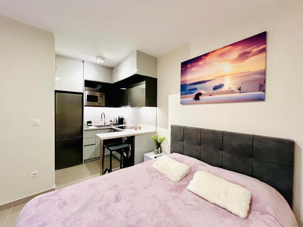 a bedroom with a pink bed and a kitchen at Modern studio in Elliniko 5 mins from metro in Athens