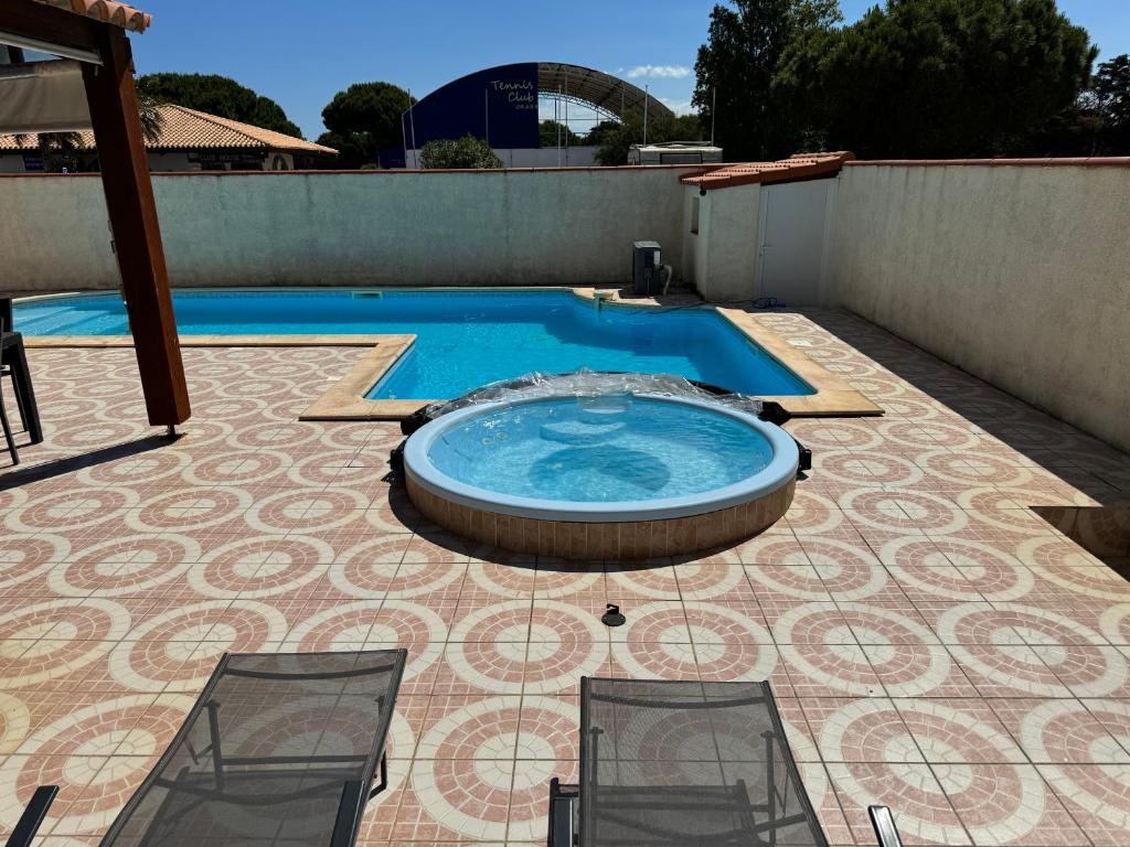 une piscine avec deux chaises sur un patio dans l'établissement Villa la lagune piscine et spa privés 8 Couchages parking privé et borne de recharge électrique, au Barcarès