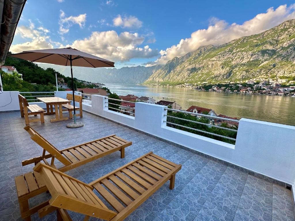uma varanda com cadeiras e um guarda-sol com vista para um rio em House with big terrace and beautiful sea view em Kotor