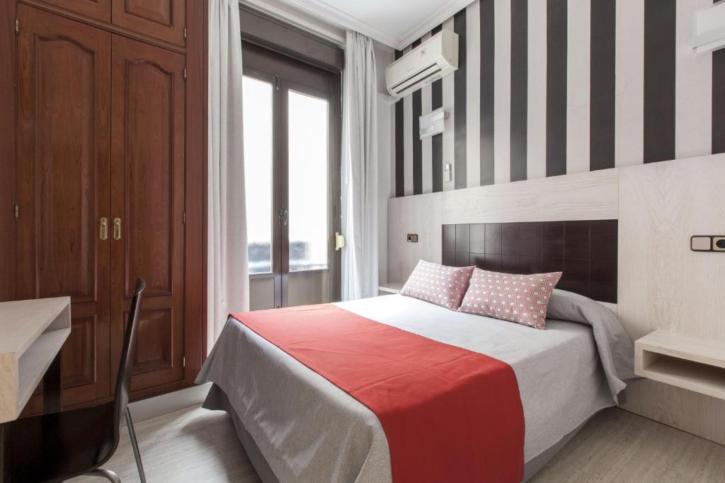 1 dormitorio con 1 cama con pared a rayas en Hostal Castilla I Atocha, en Madrid