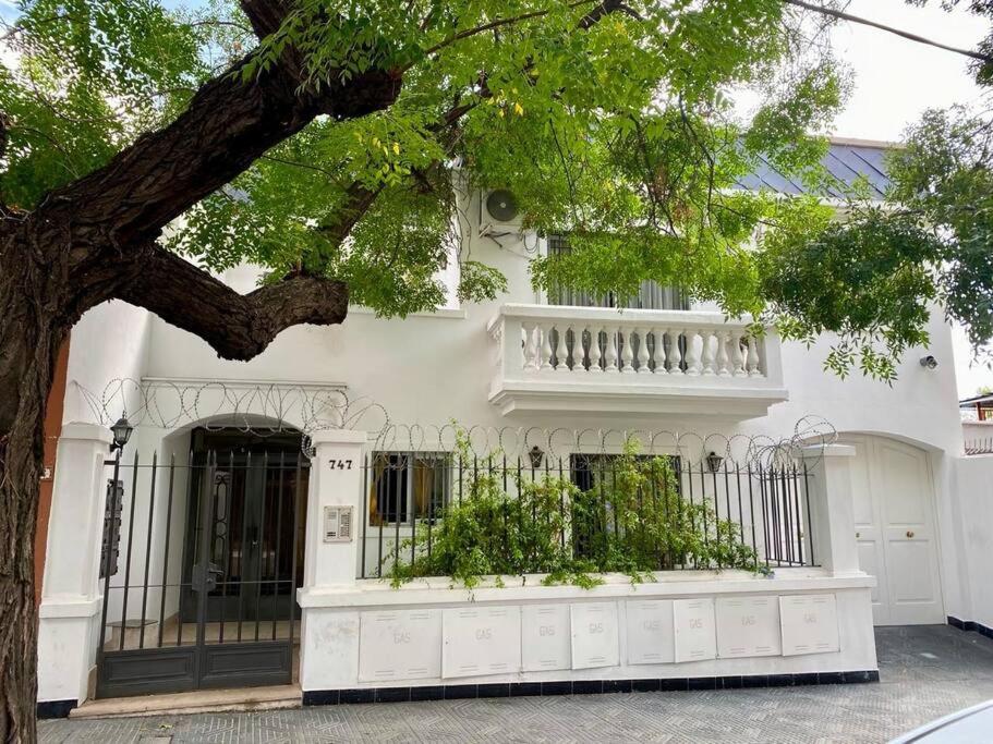 une maison blanche avec une clôture et un arbre dans l'établissement Nuevo exclusivo alojamiento en Mendoza, à Villa Marini