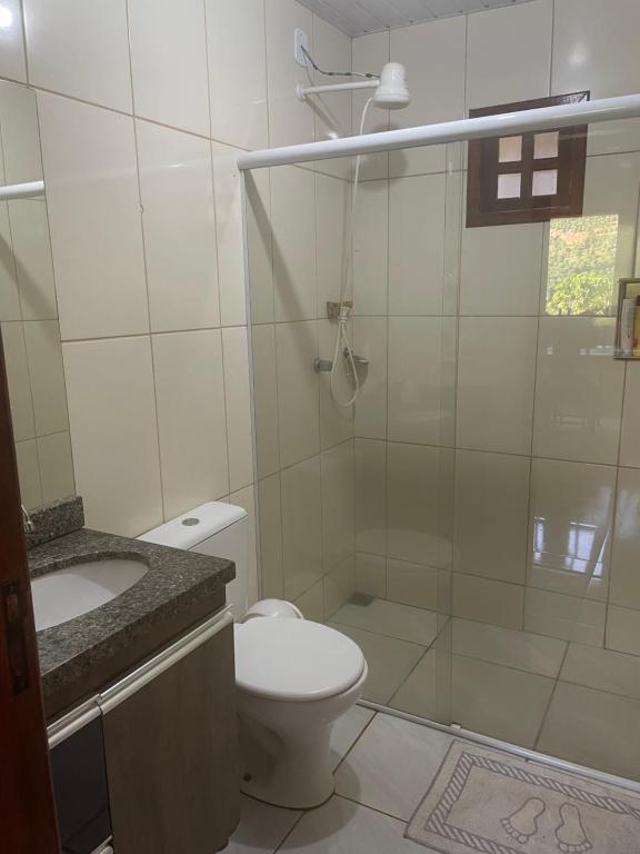 a white bathroom with a toilet and a shower at Casa de campo in Presidente Soares