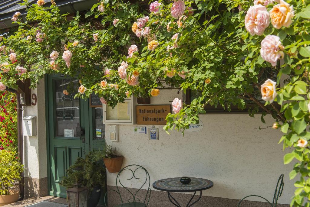 a table and chairs in front of a building with flowers at Kräuterpension Säumerpfad in Mauth