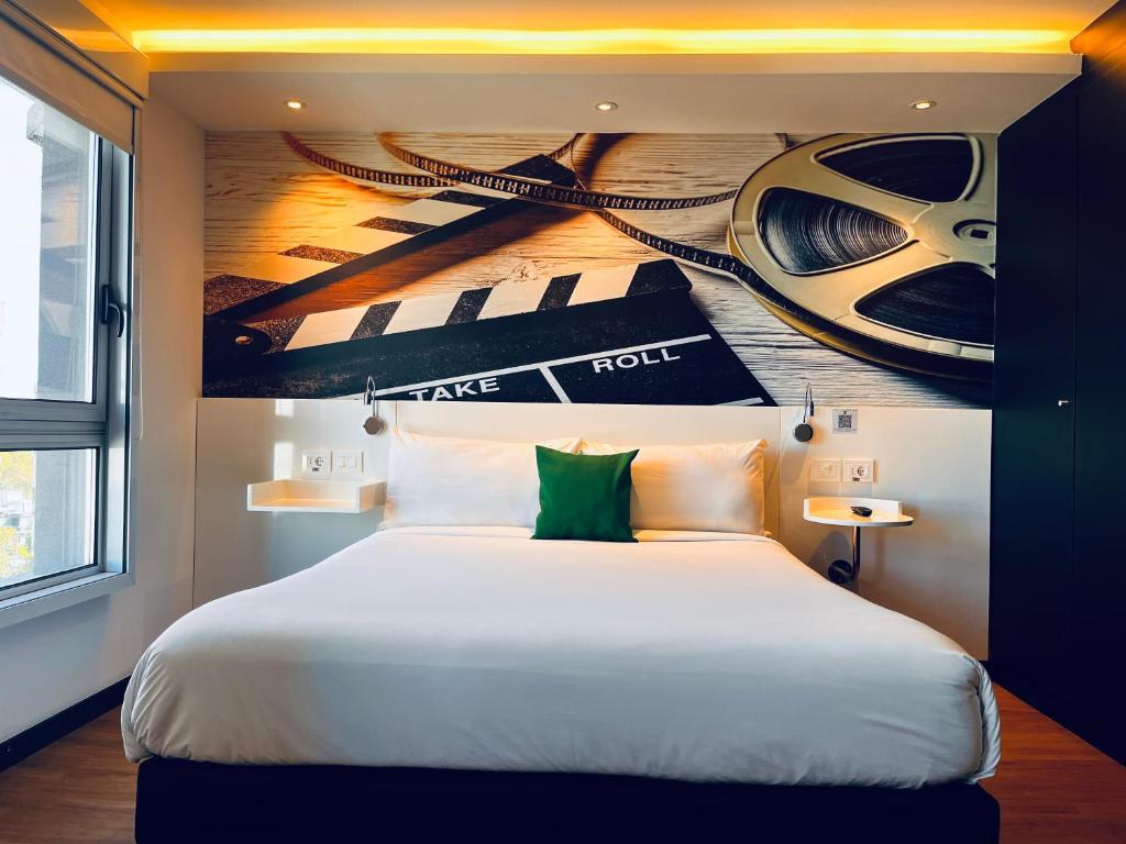 a bedroom with a large bed with a painting on the wall at ibis Styles Montevideo Biarritz in Montevideo