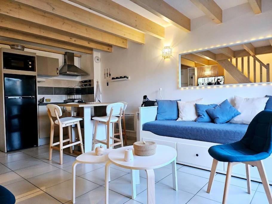 un salon avec un canapé bleu et une cuisine dans l'établissement Appartement cosy à Royan, à Royan