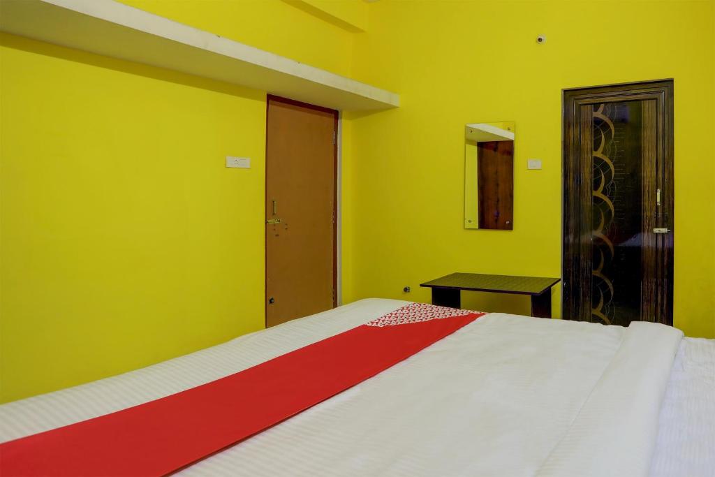 ein Schlafzimmer mit einem Bett mit gelben Wänden und einem Tisch in der Unterkunft OYO Flagship Dn Premium Villa in Jānla