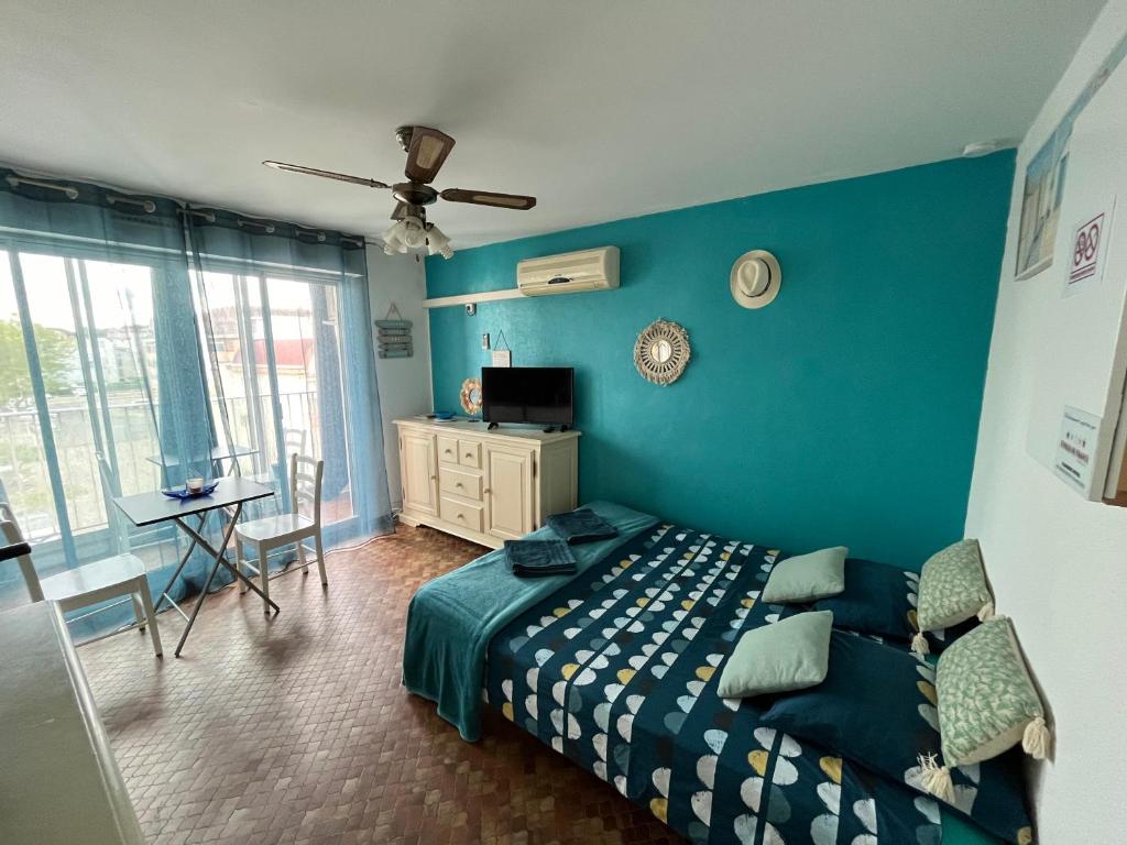 1 dormitorio con pared azul, cama y escritorio en Gruissan Holidays, en Gruissan