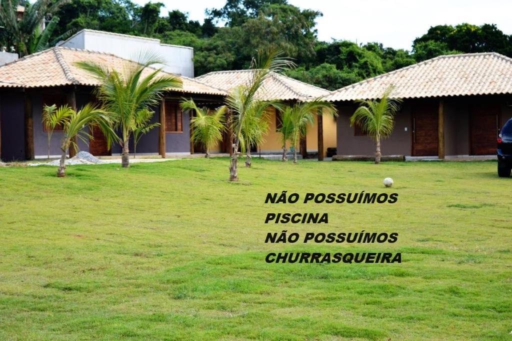 un cartel frente a una casa con palmeras en Suítes e Flats das Papoulas Ferradura In Búzios, en Búzios