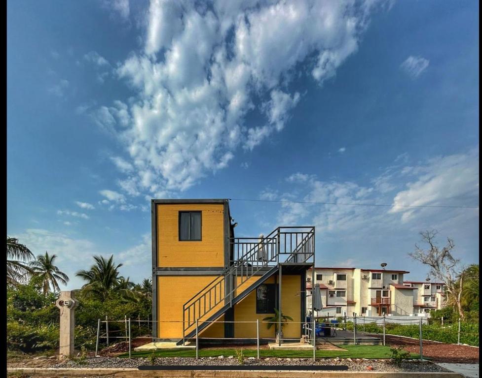 a yellow building with a staircase on top of it at Yellow house 6 minutos de playa in Barra de Navidad