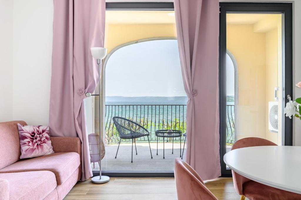 a living room with a pink couch and a balcony at Casa Vacanze Maddalena - Palazzetto sul lago - Diamante Rosa in Marta