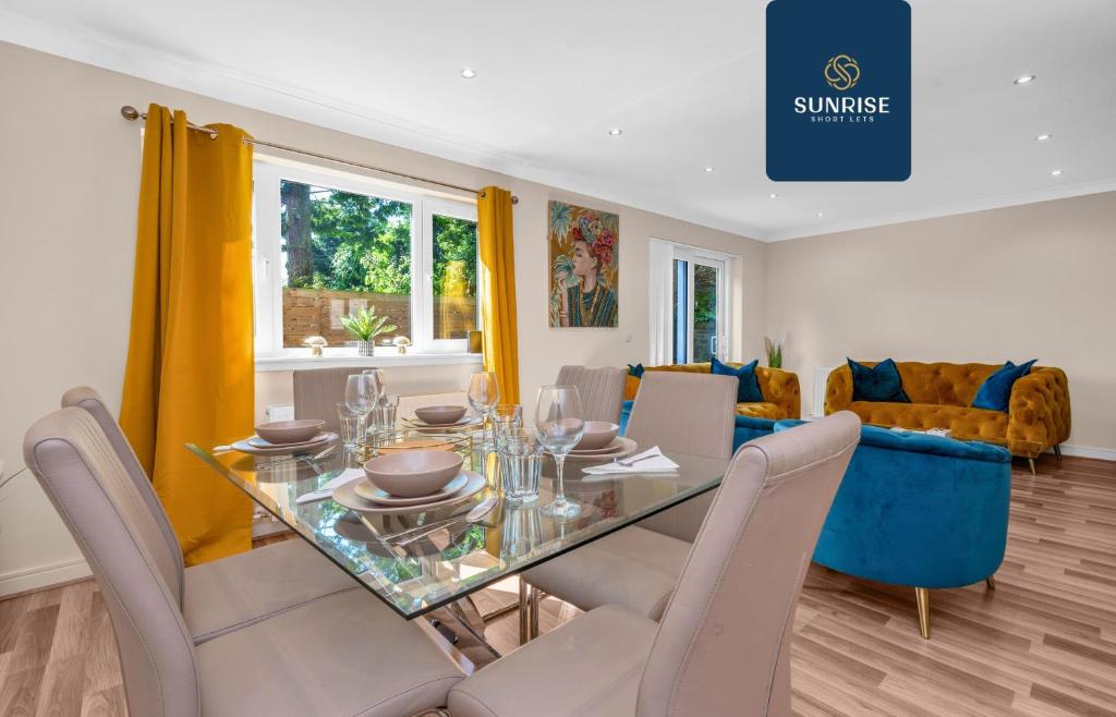 uma sala de jantar com uma mesa de vidro e cadeiras em MUIRTON HOUSE, 4 Bed House, 4 Car Driveway, 2 Bathrooms, Smart TVs in every room, Fully Equipped Kitchen, Large Dining and Living Space, Rear Garden, Free WiFi, Mid to Long Stay Rates Available by SUNRISE SHORT LETS em Dundee