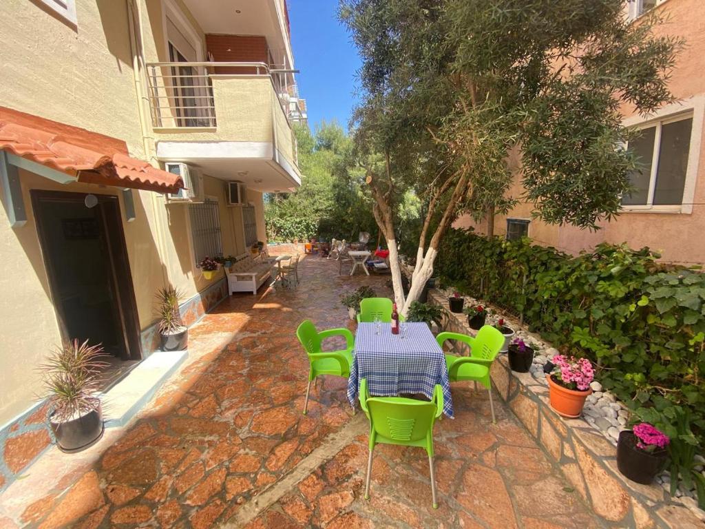 a patio with a table and green chairs at Olive Tree Apartment in Sarandë