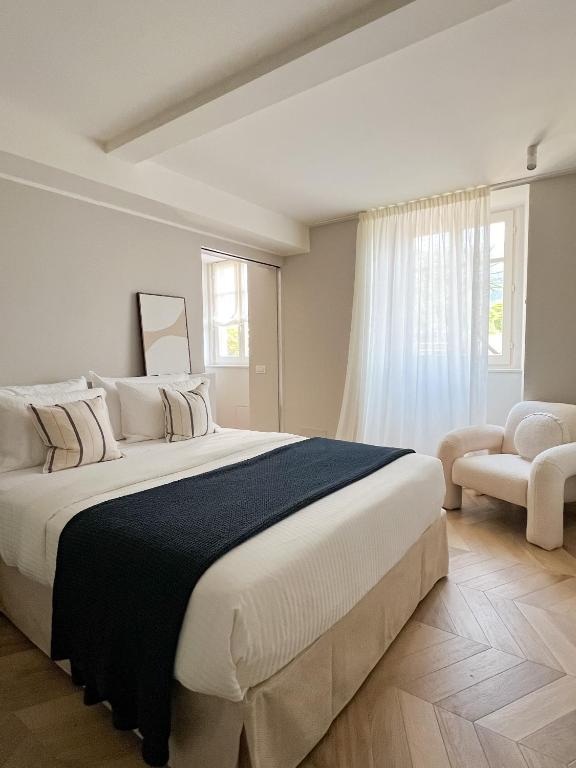 a white bedroom with a large bed and a chair at Sweet Menaggio in Menaggio