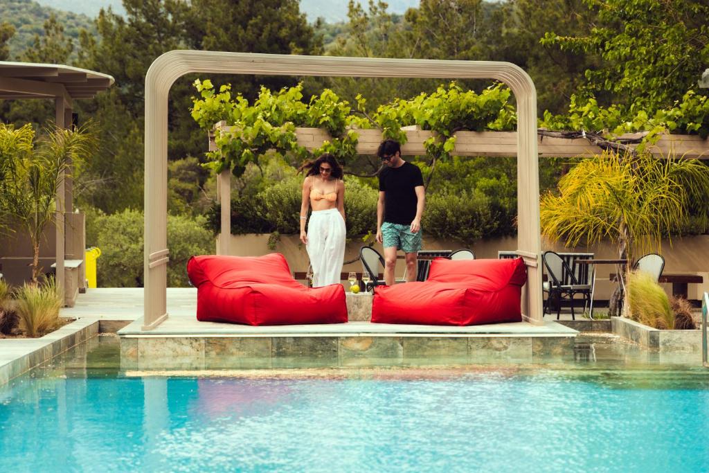 a man and a woman standing next to a pool at Zoe Hotel, Trypiti Beach Resort & Hive water park in Limenaria