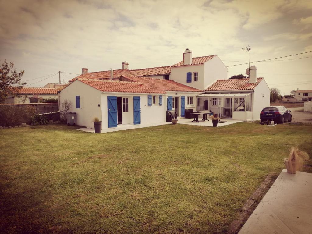 a white house with blue doors and a yard at La cousinade No in Noirmoutier-en-l'lle