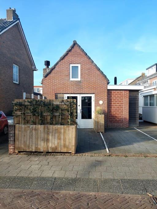 a brick house with a fence in front of it at Have a nice stay! - Beach Cottage free parking in Noordwijk aan Zee