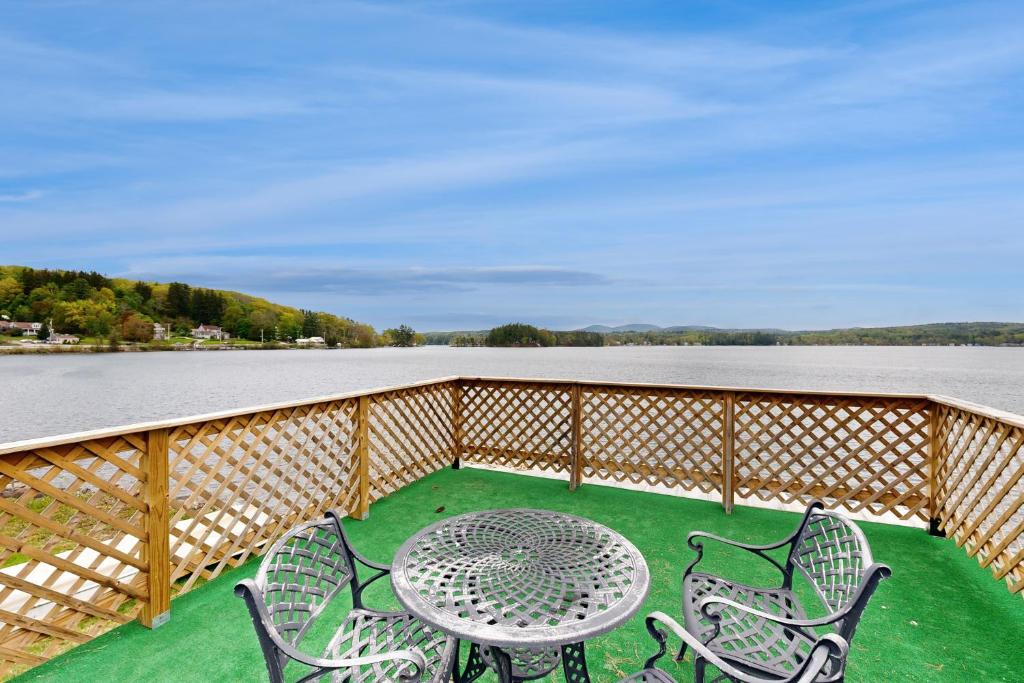 a table and chairs on a balcony with a view of the water at Winnisquam Lake Retreat in Tilton