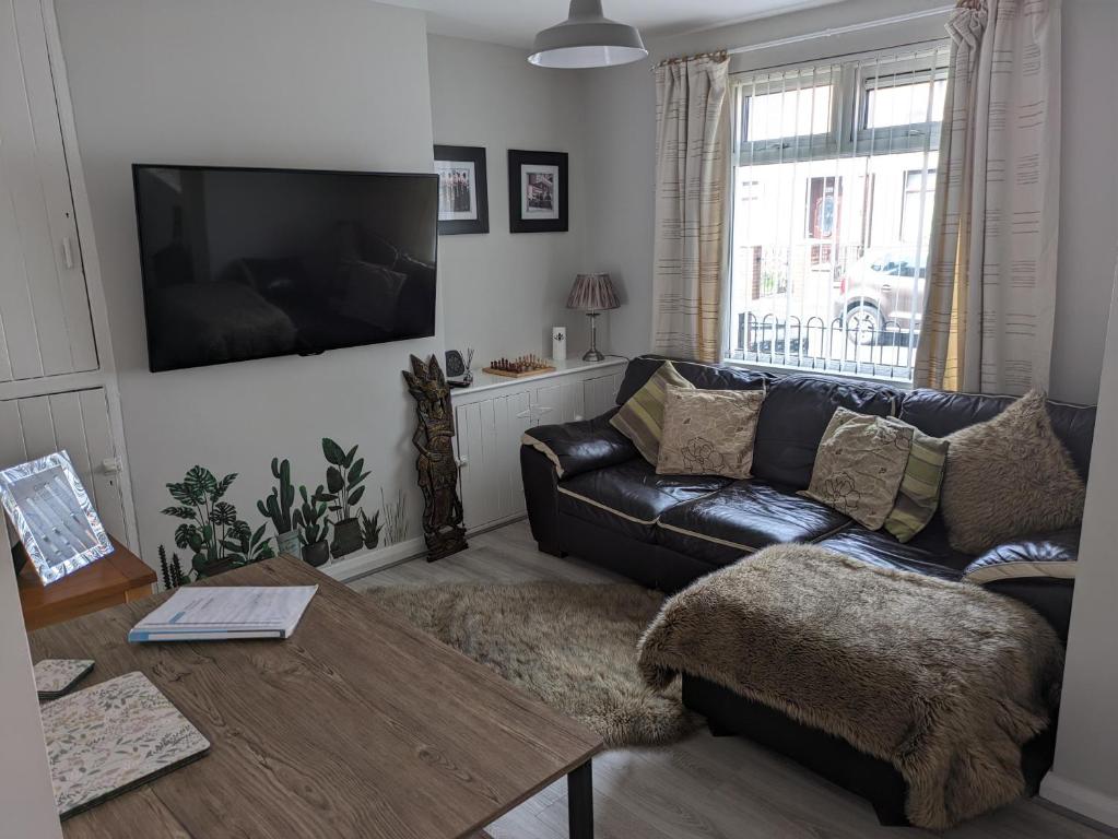 a living room with a leather couch and a table at Máire Toiréasa – cosy refurbished property in the Gaeltacht Quarter in Belfast