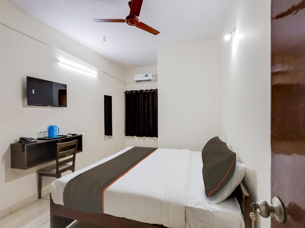 a bedroom with a bed with a ceiling fan and a desk at OYO Flagship Valasaravakkam in Chennai