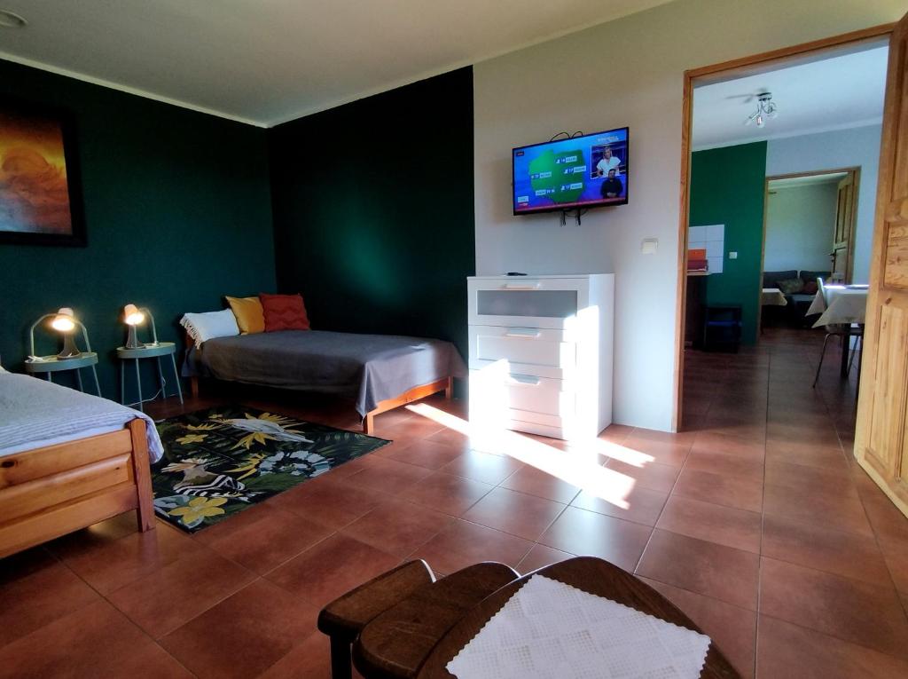 a living room with a bed and a tv on the wall at Domek w górach in Międzylesie