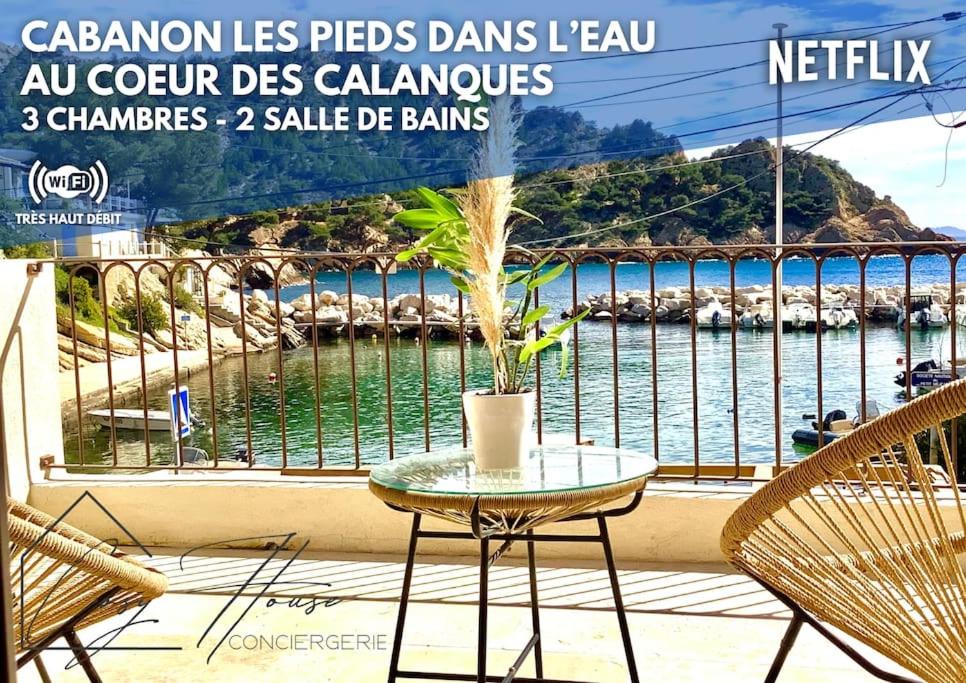 d'une table et de chaises sur un balcon avec vue sur l'eau. dans l'établissement Le Cabanon - Les pieds dans l'eau - Calanques - Wifi, à Ensuès-la-Redonne