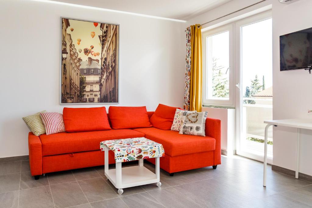 Lavender, Lighthouse, Sunrise Apartments - Kuća&More House No13 في كرك: غرفة معيشة مع أريكة حمراء وطاولة