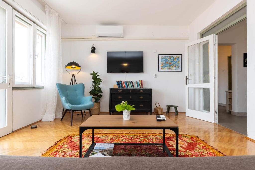 a living room with a table and a blue chair at Enolabee in Mali Lošinj