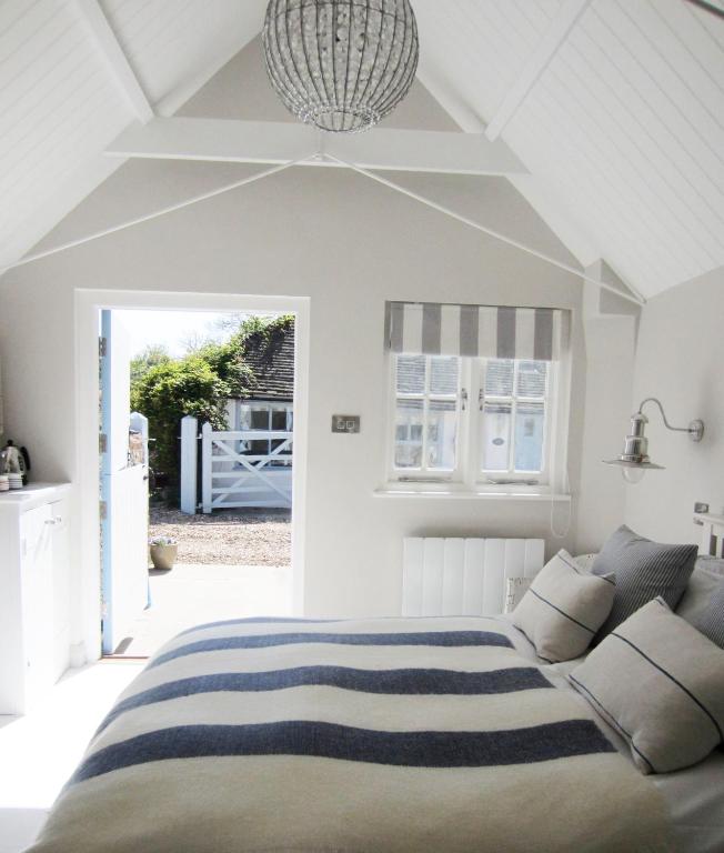 a white bedroom with a bed and a couch at The Sailor's House at Blue Door Barns in Beddingham