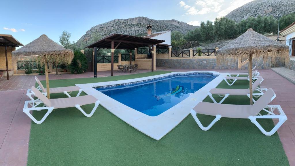 een villa met een zwembad en 2 ligstoelen bij El Rincón de Caminito del Rey in Valle de Abdalagís