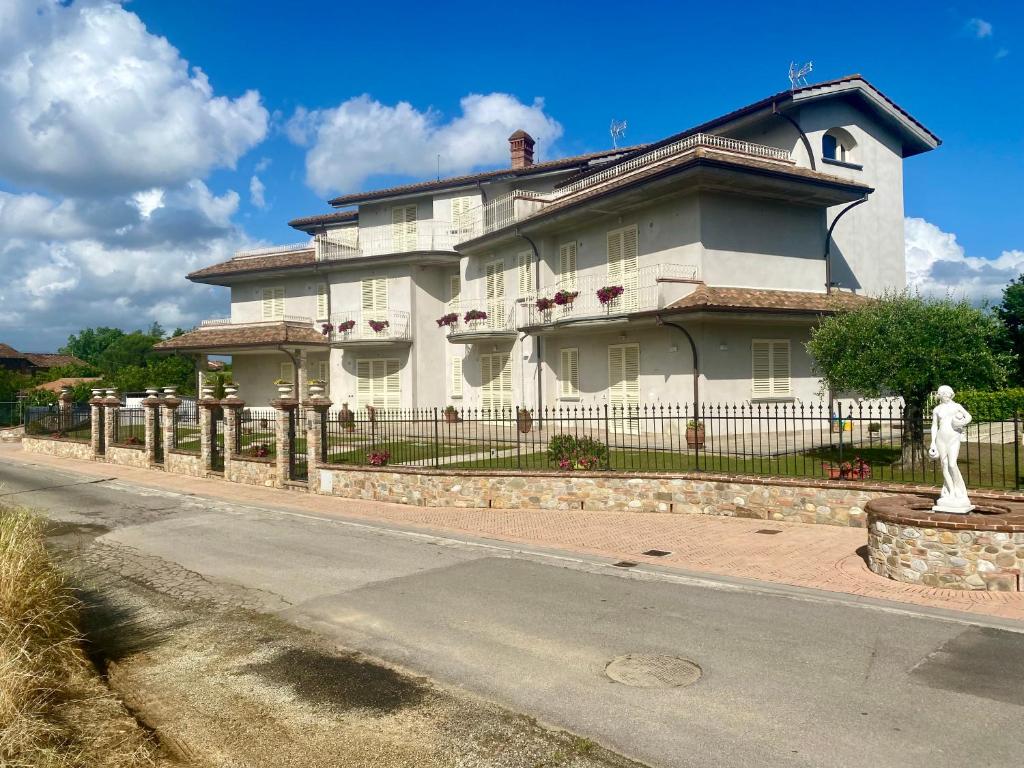 une grande maison blanche avec une clôture et une statue dans l'établissement -Casa Vacanza Il Glicine- Immerso Nel Verde, à Altopascio
