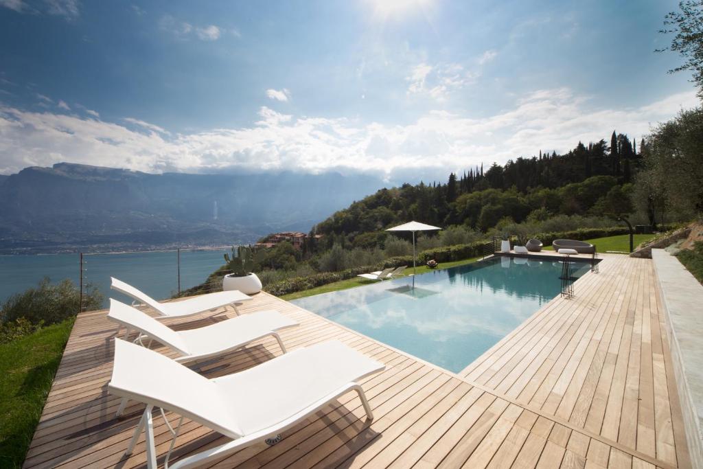 a swimming pool with white chairs on a wooden deck at Residence Relais Cà dell'Era in Tremosine Sul Garda