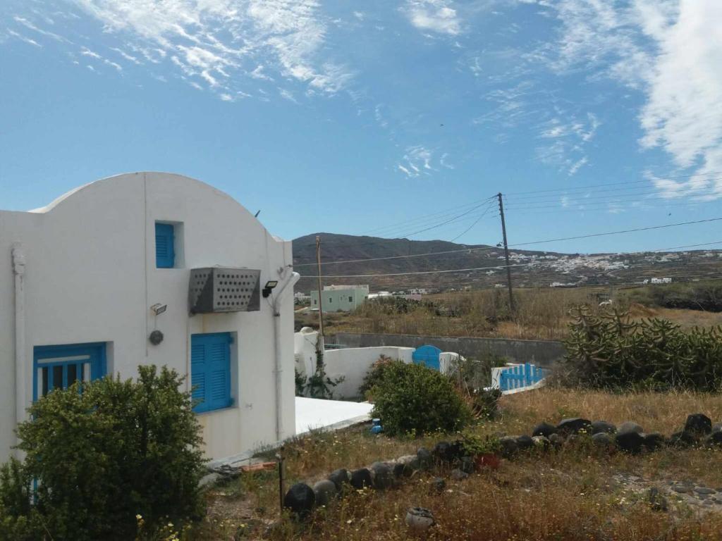 a white house with a blue door and a hill at Paradise Serenity in Thólos