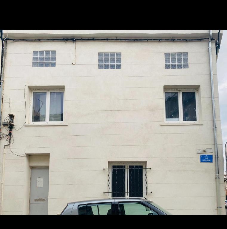 un bâtiment blanc avec des fenêtres et une voiture garée devant dans l'établissement Maison Barbini, à Marseille