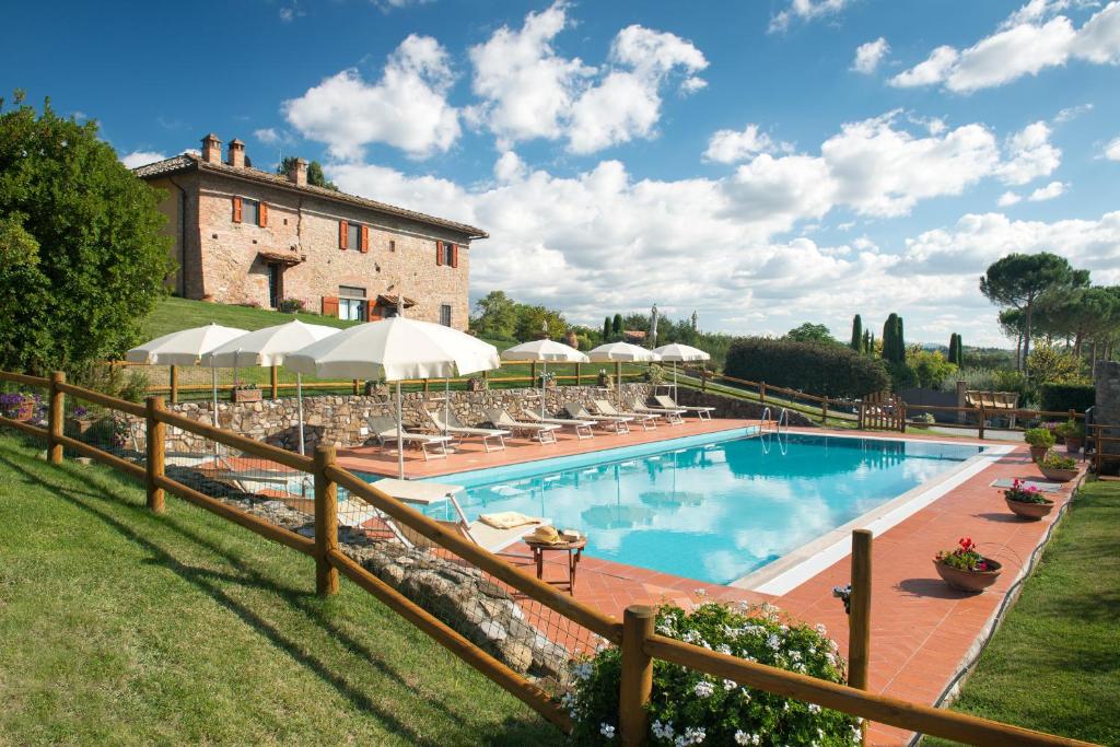 una piscina con sedie e ombrelloni di fronte a un edificio di Il Coltro a San Gimignano